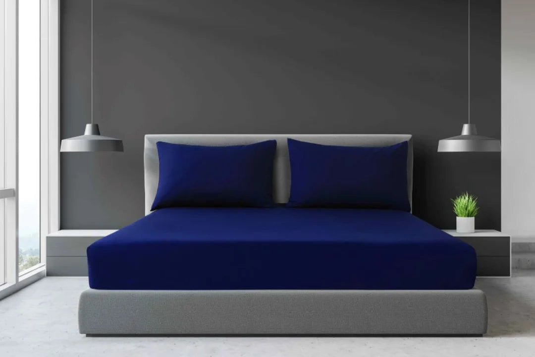 Navy blue King, Super King and California King percale fitted sheet set with matching pillowcases on a large hospitality bed.