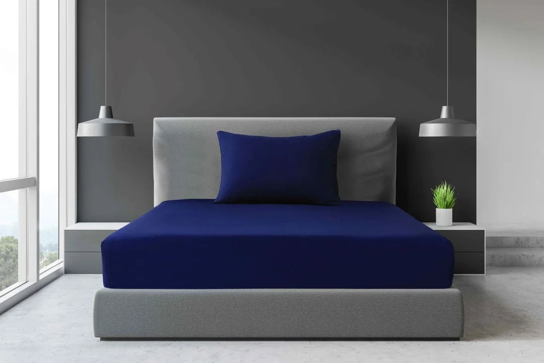 Navy blue Single and King Single percale fitted sheet with matching pillowcase displayed on a modern accommodation bed.
