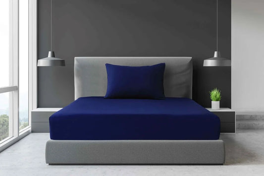 Navy blue Single and King Single percale fitted sheet with matching pillowcase displayed on a modern accommodation bed.